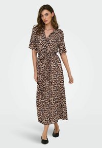 Robe maxi en tissu imprimé léopard, dotée de manches courtes, d'un col et d'une taille ceinturée. Les accents notables incluent une texture douce et un design fluide.