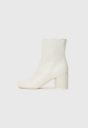 White leather ankle boot with rounded toe and chunky cylindrical heel. Smooth texture, minimal design, no visible hardware or patterns.