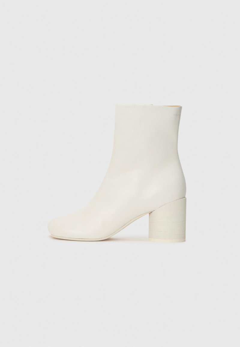 Bottine en cuir blanc avec bout rond et talon cylindrique épais. Texture lisse, design minimal, sans matériel ni motifs visibles.