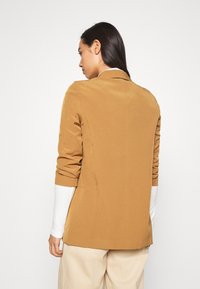 Brown, tailored blazer with a single-button closure, structured shoulder, and rolled sleeves, made of smooth fabric with a sleek finish.