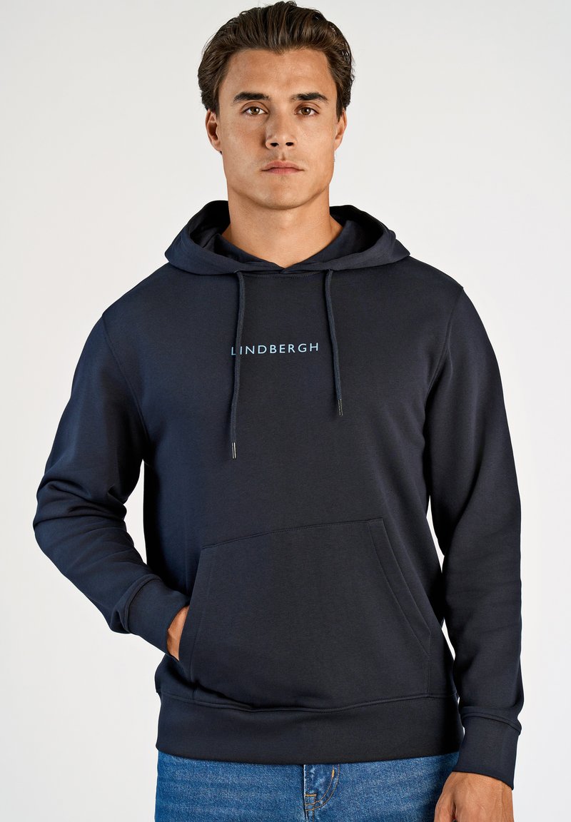 Marineblauwe hoodie met trekkoord; heeft een voorzak en een "LINDBERGH"-logo in lichtblauw op de borst. Gemaakt van zachte stof.