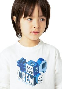 Camicia bianca a maniche lunghe con un design grafico blu che presenta forme e il testo "ACTIVE @ HI!" e "CREW", inclusi faccine sorridenti e hashtag.
