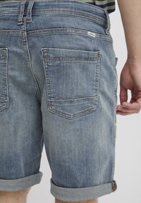 Džínové šortky vo vyblednutej svetlomodrej farbe, s obrúbenými manžetami, piatimi vreckami a kontrastným prešívaním. Zadné vrecká majú jedinečný dizajn.