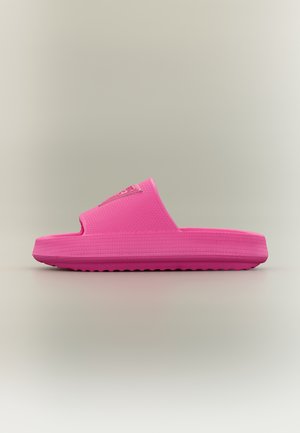 Sandalone rosa acceso con suola testurizzata e fascia larga, mostrato di profilo su uno sfondo neutro.