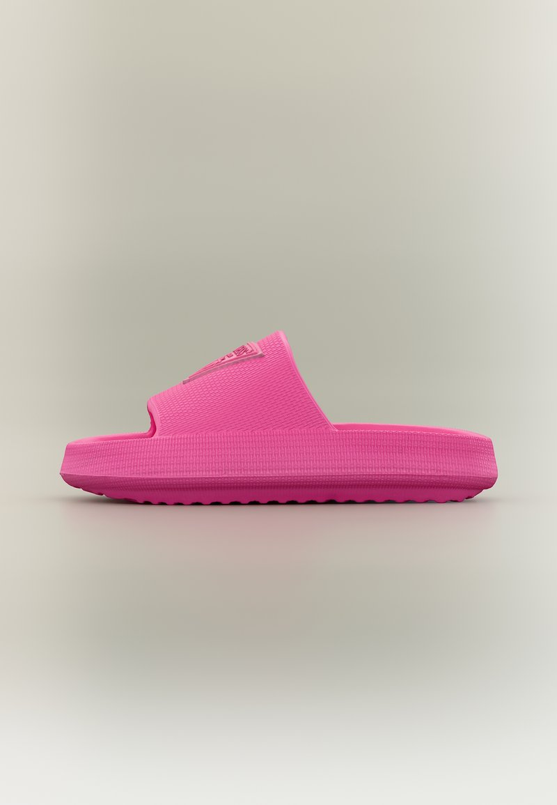 Világos rózsaszín, felcsúsztatható papucs texturált talppal és széles pánttal, oldalnézetből, semleges háttér előtt.