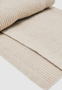 Textureret beige stof med et ribbet design, der har rullede kanter. Materialet fremstår blødt og lidt fuzzy med en ensartet farve.