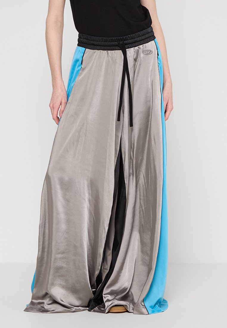 Pantalons à jambe large avec un devant métallique argenté brillant, une taille noire avec cordon de serrage et des panneaux latéraux bleus. Texture lisse et design sportif.