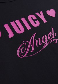 Fekete szövetpóló élénk rózsaszín felirattal: "JUICY" és alatt egy díszes írásmóddal az "Angel" felirat. Simább textúra, hétköznapi megjelenés.