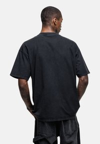 Zwarte katoenen oversized t-shirt met korte mouwen, een ronde hals en een zachte textuur. Eenvoudig ontwerp, geen zichtbare patronen of accenten.