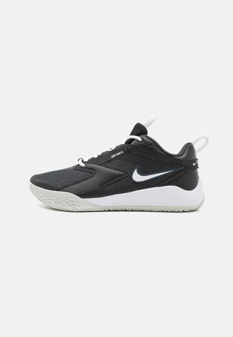 Čierne športové topánky s textúrovaným zvrškom, bielym logom Nike na boku, kontrastnou bielou podrážkou a šnúrokami. Obsahujú pútko na zadnej strane.