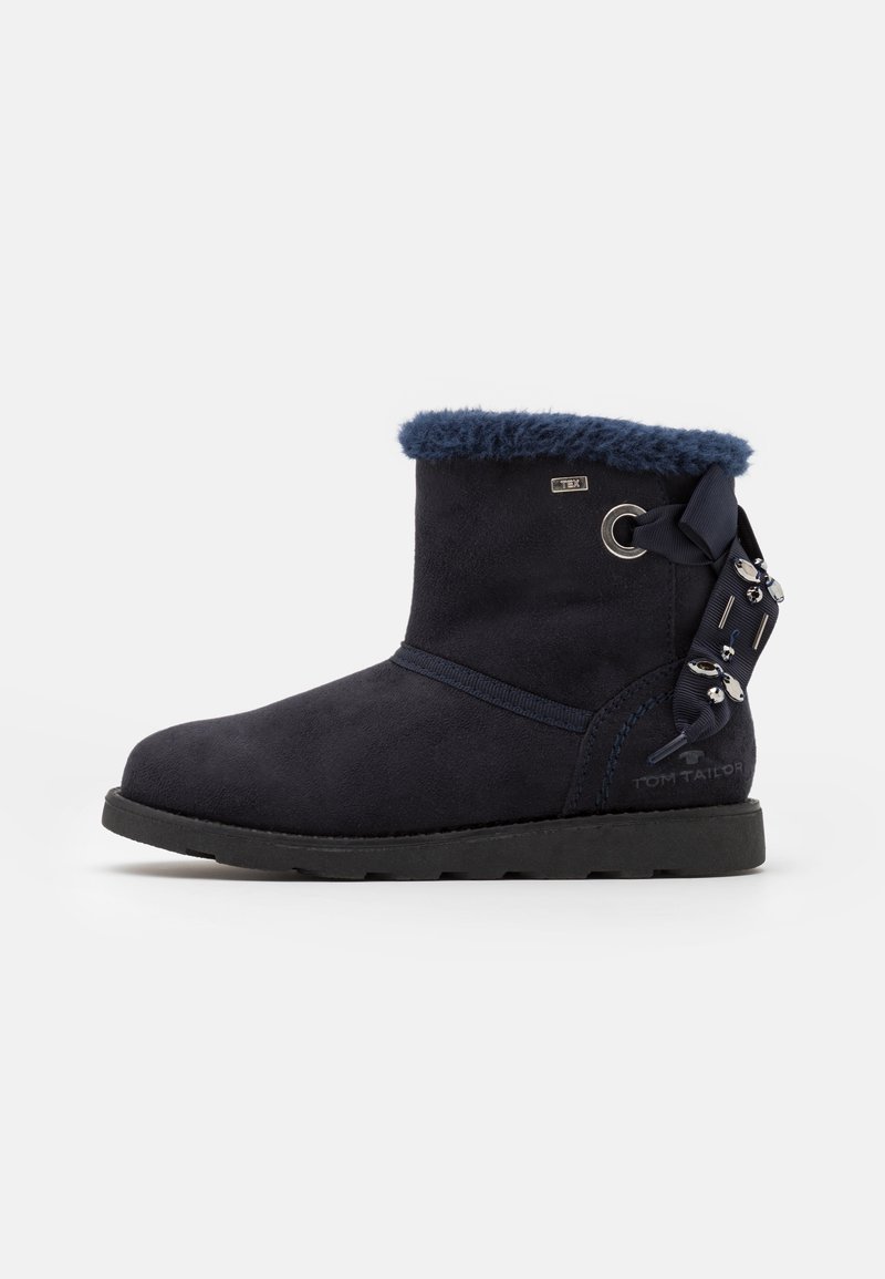 Bottines en suède bleu marine avec un col en fausse fourrure, détail de ruban sur le côté et semelle en caoutchouc noir texturé. Marque sur le côté.