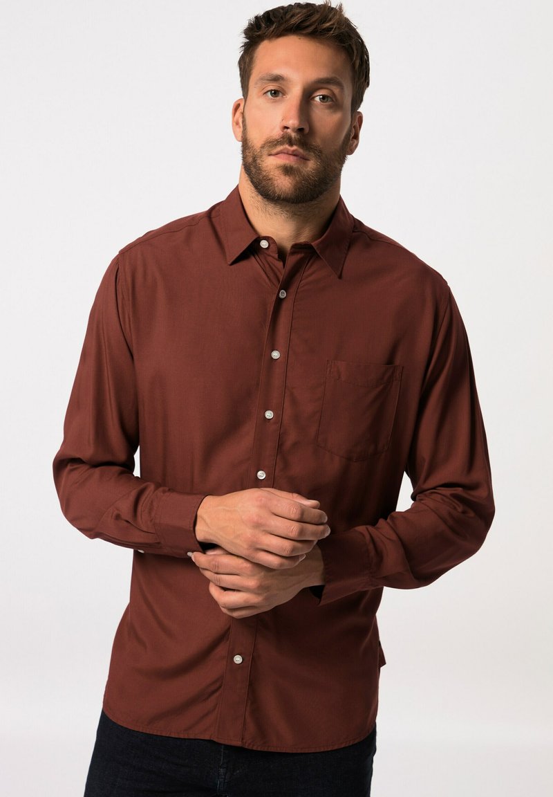 Camicia a maniche lunghe in tessuto rustico scuro, con colletto, chiusura a bottoni e tasca sul petto. Texture liscia, vestibilità sagomata, con polsini abbottonati.