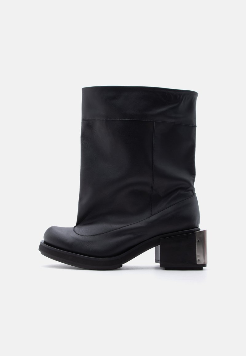 Μαύρη δερμάτινη μπότα μέσου μήκους με στρογγυλεμένη μύτη και χοντρό τακούνι που διαθέτει μεταλλικές λεπτομέρειες στην πίσω πλευρά.