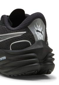 Scarpa sportiva nera con tessuto testurizzato, accenti riflettenti e suola chunky. Presenta un logo e un motivo ondulato nel design superiore.