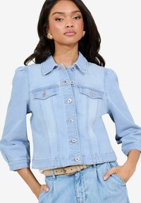 Giacca di jeans azzurro chiaro con un design strutturato, dotata di colletto, tasche anteriori e chiusure a bottoni; leggera e con una consistenza morbida.