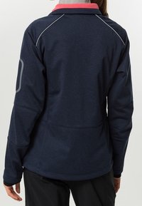 Chaqueta de forro polar en azul marino con un cuello rosa. Presenta costuras en contraste, un corte ajustado y acentos reflectantes en las mangas y la parte trasera.
