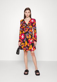 Vestido floral com mangas longas, apresentando flores vibrantes em laranja, rosa e verde sobre um fundo preto. Inclui um decote em V profundo.