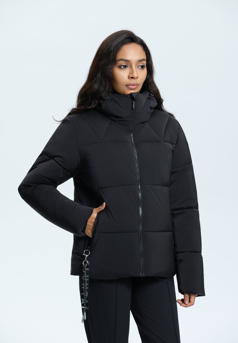 Schwarze Puffjacke mit Kapuze, ausgestattet mit einem Reißverschluss vorne, geometrischer Steppung und Seitentaschen. Mit einem dekorativen Hardware-Detail akzentuiert.