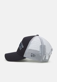 Navy baseball cap with a solid front, mesh back, and embroidered text. Features a curved brim and a brand logo on the side.