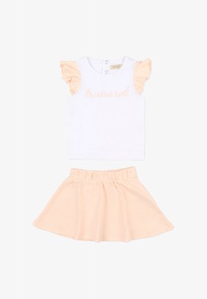 Top blanco sin mangas con mangas fruncidas en color melocotón y texto "trussardi", combinado con una falda a juego en melocotón con cintura elástica para niños.