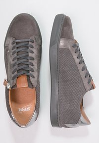 Graue Wildledersneaker mit strukturierten grauen Einsätzen, braunen Lederakzenten, metallic silbernem Fersendetail und grauen Schnürsenkeln. Reißverschlussverschluss an der Seite.