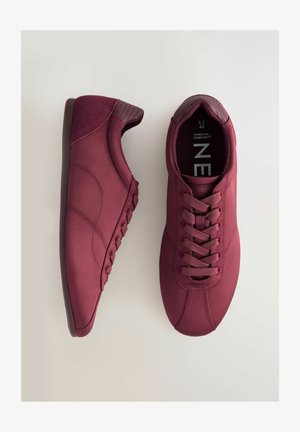 Burgunderfarbene Sneaker aus glattem Material, mit rundem Zehenbereich und tonal passenden Schnürsenkeln. Ausgestattet mit einem gepolsterten Knöchelkragen und einem strukturierten Fersenakzent.