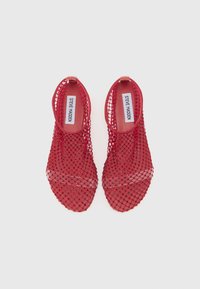Red open-toe shoes made of netted material, featuring a smooth inner lining and a minimalistic design with no visible hardware or accents.