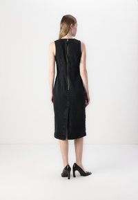 Black denim fitted dress with a high neckline, sleeveless design, and a central back zipper. Features a mid-length skirt with a back slit.