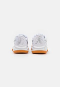 White athletic shoes with light gray accents, textured mesh and solid rear, featuring an orange rubber outsole. Minimalistic design.