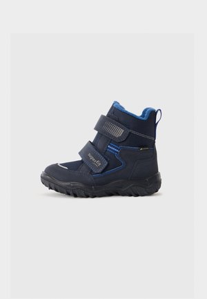 Bota de inverno para crianças, azul marinho, com sola preta, duas tiras de Velcro, forro azul e etiqueta Gore-Tex na lateral.