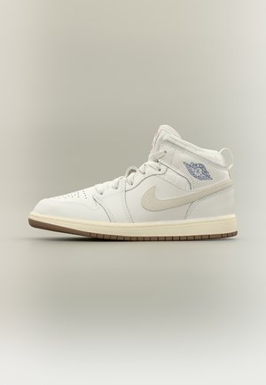 Biele vysoké tenisky s béžovou podrážkou, béžovým logom Nike Swoosh, modrým logom Air Jordan na boku a bielymi šnúrkami na jednoduchom neutrálnom pozadí.