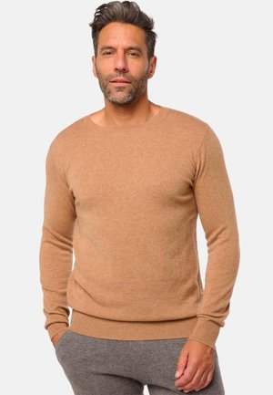 Pull à col rond, à manches longues, en tricot doux de couleur marron clair. Présente des poignets et un ourlet côtelés pour un aspect ajusté.