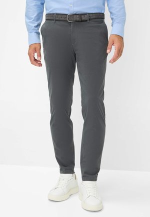 Dunkelgraue Hose aus glattem Stoff, mit einer taillierten Passform, Gürtelschlaufen und einem strukturierten schwarzen Gürtel. Kombiniert mit weißen Sneakers.