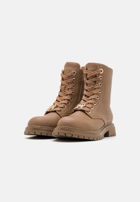 Brune lær ankle støvler med snørebånd, rund tå, kraftig såle og en gullmetallaccent på tungen, med en glatt tekstur.