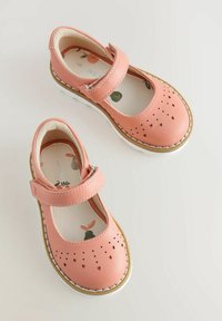 Różowe skórzane buty Mary Jane z jedną paskiem, z perforowanym wzorem serca na palcach oraz białą gumową podeszwą. Miękka podszewka.