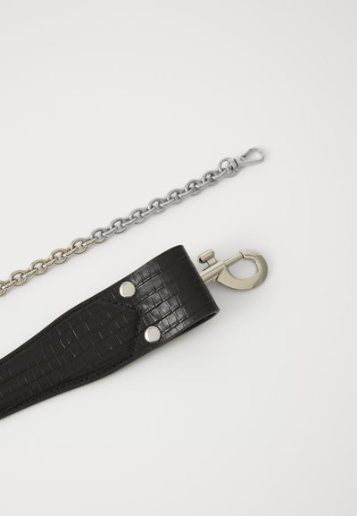 Correia de couro texturizado preto com hardware prateado e botões de pressão, acompanhada de uma corrente prateada. A correia inclui um clip para fixação.