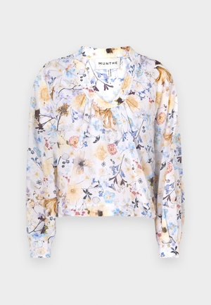Blus bermotif floral dalam bahan ringan, dengan leher berbentuk V, lengan panjang, dan detail kerut di leher dalam warna pastel.