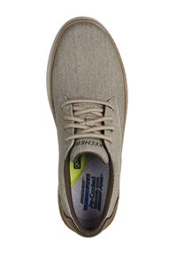 Sneaker in tela beige con superficie testurizzata, punta tonda, lacci marroni e suola in gomma; presenta una soletta imbottita con dettagli del logo.