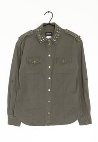 Oliwkowa koszula z kolczastym kołnierzem, dwoma przednimi kieszeniami i mosiężnymi guzikami. Długie rękawy z możliwością podwinięcia i zaokrąglony dół.