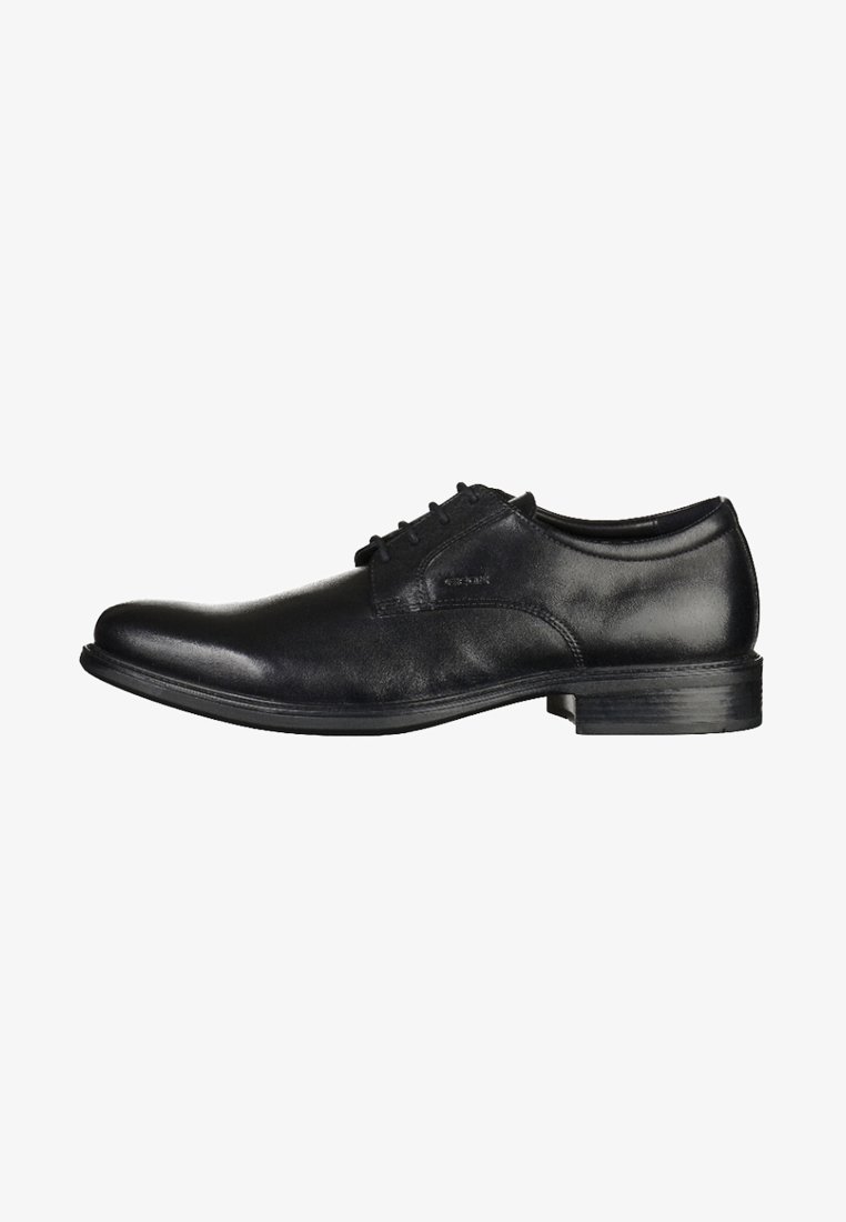 Zapato de vestir de cuero negro con textura suave, punta redondeada clásica y diseño de cordones. Presenta un tacón bajo y apilado con acentos minimalistas.