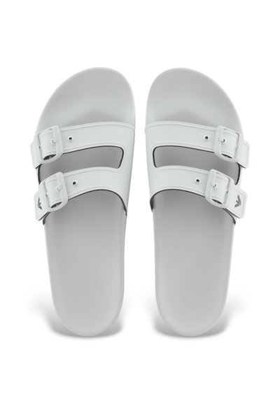 Sandali bianchi con doppie fibbie regolabili, design piatto, texture liscia e soletta sagomata per il comfort. Adatti per un abbigliamento casual.