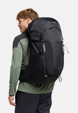 Zaino nero con un design strutturato, dotato di spallacci regolabili e finitura testurizzata. Le rifiniture includono una tasca con zip e dettagli del logo.