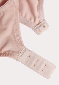 Cinghia e gancio di un reggiseno rosa chiaro, caratterizzati da una texture in tessuto con bordi lisci e cuciture rinforzate. Chiusura a gancio e occhiello regolabile visibile.