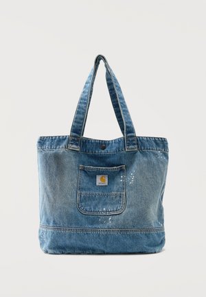 Borsa tote in denim con doppi manici, tasca frontale con logo Carhartt e dettagli di schizzi di vernice bianca su tessuto blu sbiadito.