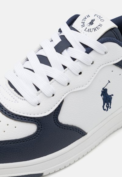 Zapatillas blancas y marinas con una parte superior de cuero suave, punta redonda y cordones blancos. Presentan un logo marino bordado en el costado.
