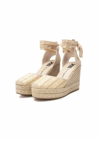 Alpargatas de cuña con parte superior de yute natural tejido y correas de tela beige. La puntera cuadrada y la plataforma cubierta de cuerda añaden textura y altura.