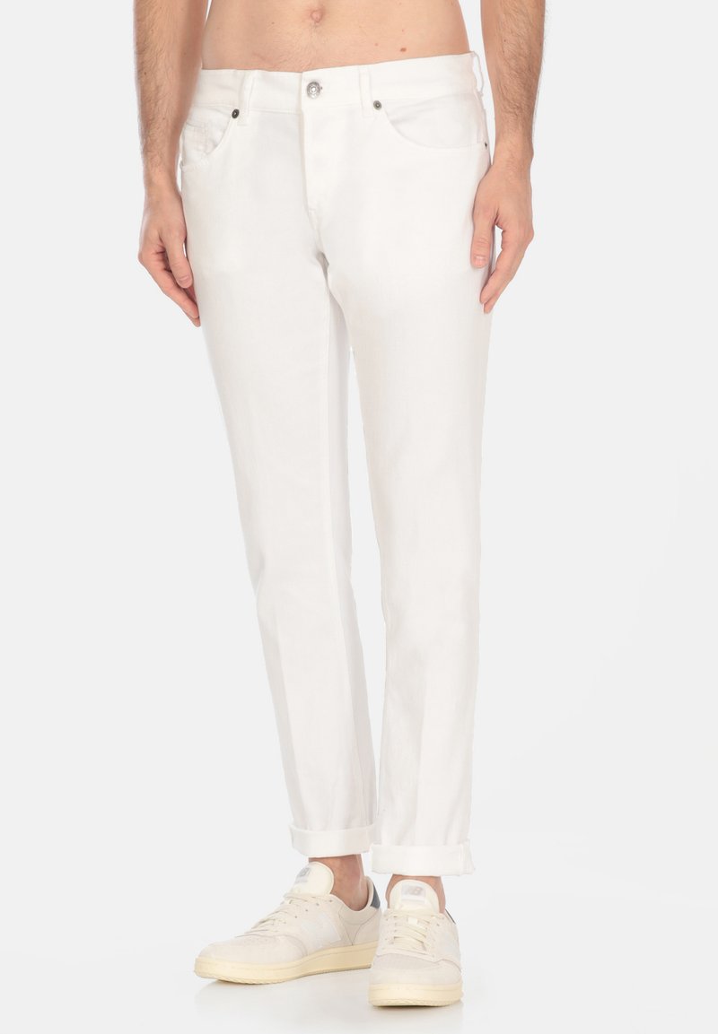 Pantaloni in denim bianco con vestibilità dritta, cinque tasche, chiusura con bottone argentato e risvolti. Indossati con sneakers beige.