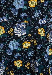 Kukkaistyyppinen kangas tummansinisellä taustalla, jossa on suuria sinisiä ja keltaisia kukkia, vihreitä lehtiä sekä herkkiä pienempiä kukkia ympäriinsä.