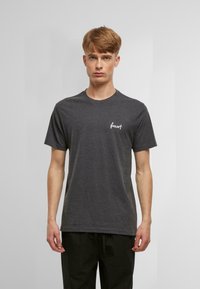 Grau Baumwoll-T-Shirt mit kurzen Ärmeln, Rundhalsausschnitt, mit weißem Textlogo im linken Brustbereich, glatte Textur und lockere Passform.