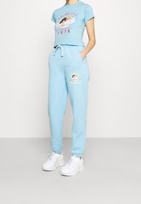 Ljusblå, kortärmad t-shirt med grafiskt tryck, ihop med matchande blå joggers med logotypdetalj. Avslutad med vita sneakers.